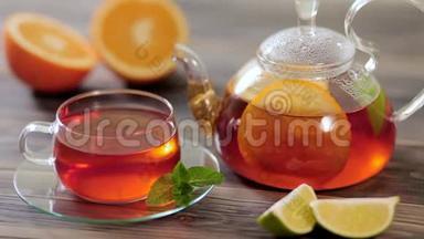 玻璃茶壶和一杯黑茶，上面放着橘子、柠檬、石灰和薄荷